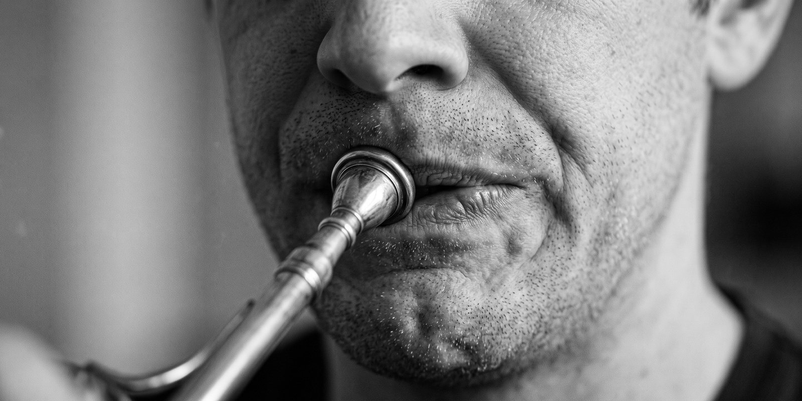 Der Ansatz eines Hornisten: die Lippen zur Seite gezogen, das Kinn verkrampft.