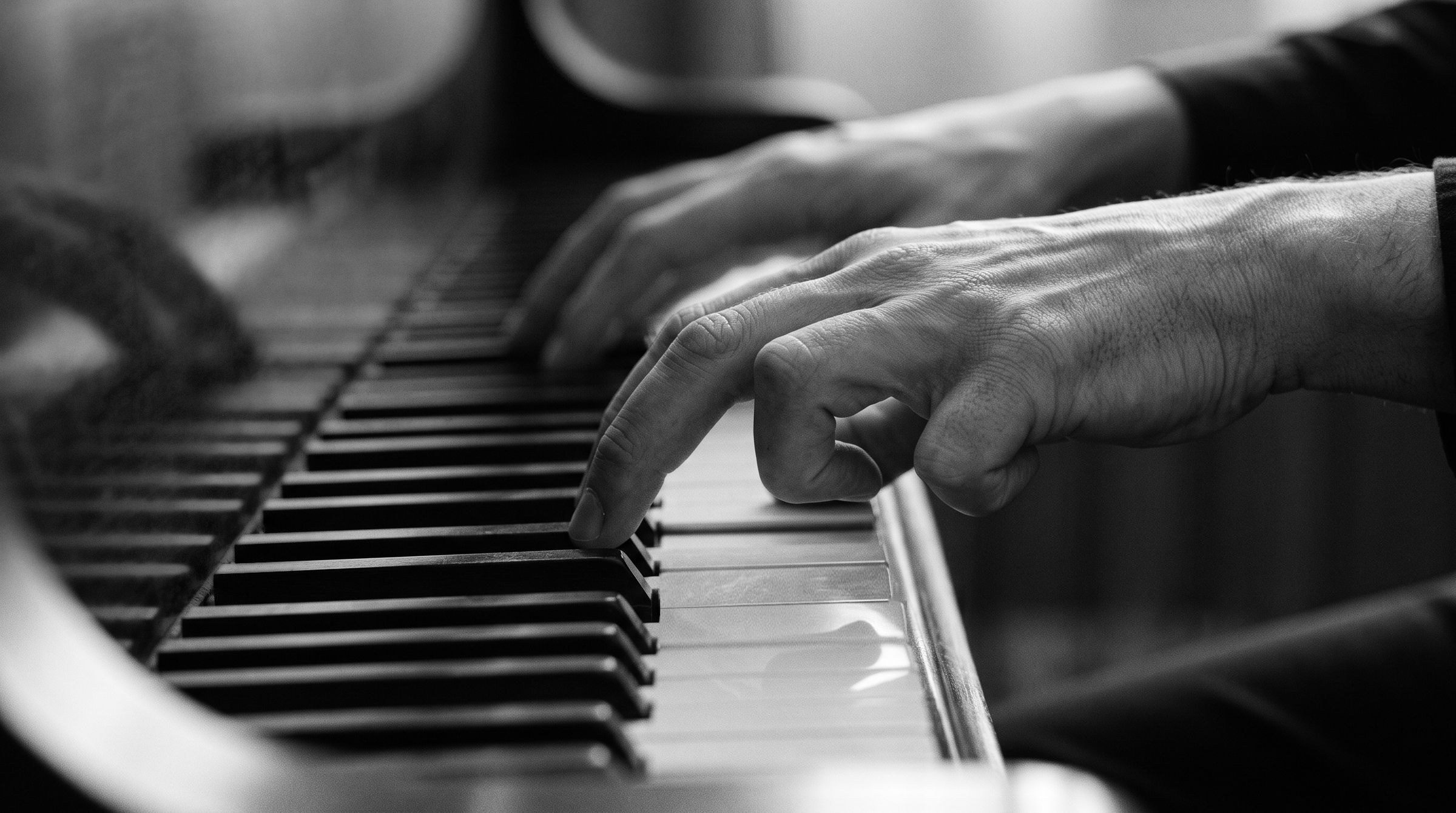 Die Hände eines Pianisten auf der Tastatur: An der rechten Hand krümmen sich Ring- und Kleinfinger unwillkürlich unter die Handfläche.
